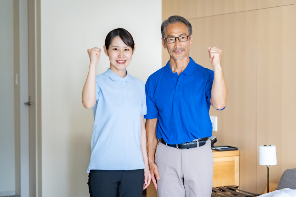 こちらを向いてガッツポーズをしている壮年の男性と若い女性